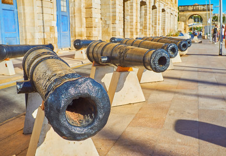 The vintage cannons decorate the Xatt Il-Forn promenade in front of Maritime museum and attract tourists to visit this historical mansion, Birgu (Vittoriosa), Malta.のeditorial素材