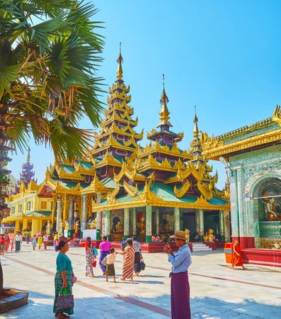 YANGON, MYANMAR - FEBRUARY 27, 2018: The masterpiece pyatthat roofs of Image Houses at Shwedagon Zedi Daw with rich gilt carvings, colorful wooden panels and ringing hti umbrellas on the top, on February 27 in Yangon.のeditorial素材