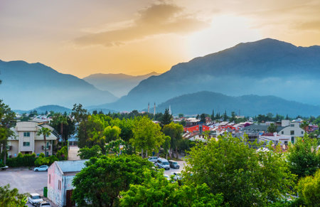 The scenic sunset sky over the silhouettes of foggy Taurus mountains with Kemer cityscape on the foreground, Turkey.のeditorial素材