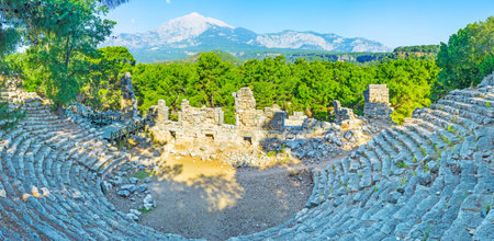 Panorama of ancient Roman amphitheatre in Phaselis with lush pines and snowbound Mount Tahtali behind the stage, Tekirova, Turkey.のeditorial素材