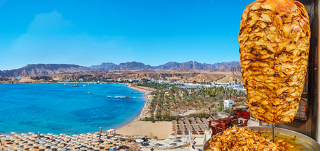 The spit-roasted grilled chicken shawarma - the popular street food and cafe dish with a view on Sharm El Maya harbor on the background, Sharm El Sheikh, Sinai, Egypt.の写真素材
