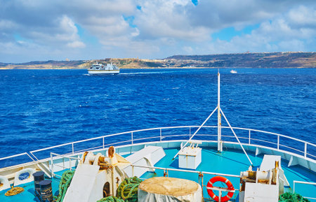The ferries, running between Malta and Gozo Islands, with a view on dark blue waters, heavy clouds and Mgarr harbour on the distance, Ghajnsielem, Gozo, Malta.のeditorial素材