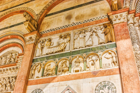 The beautiful decorations and sculptures on the wall of the portico of Lucca Doumo, Italyのeditorial素材