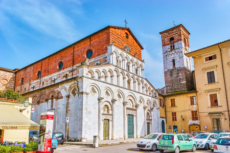 LUCCA, ITALY - APRIL 30, 2013: The medieval Santa Maria Forisportam Church with incomplete marble frontage and small bell tower on the neighbor building, on April 30 in Luccaのeditorial素材