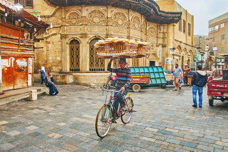 CAIRO, EGYPT - DECEMBER 21, 2017: Traditional bread delivery in old town - the cyclist with large wooden basket rides next to  Sabil wa Kuttab of Tusun Pasha in Al-Muizz street, on December 21 in Cairo.のeditorial素材