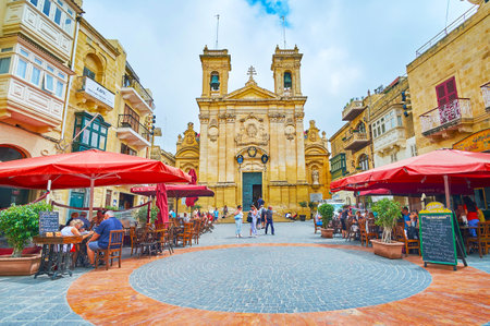 VICTORIA, MALTA - JUNE 15, 2018: Ensemble of St George square with medieval building of San Gorg basilica, old mansions and outdoor cafes, on June 15 in Victoria.のeditorial素材