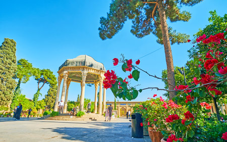SHIRAZ, IRAN - OCTOBER 13, 2017: The lview on scenic pavilion of the Tomb of Hafez through the blooming bush of bougainvillea, Mussala gardens, on October 13 in Shiraz.のeditorial素材