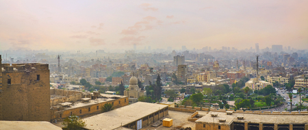 The view from the top of Saladin Citadel on its walls, greenery of Salah El-Deen Square, small dome of Mustafa Kamil Museum and the old urban neighborhoods in heavy fog, Cairo, Egypt.の写真素材