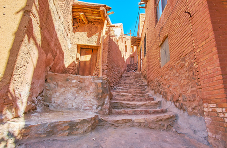 The old stone staircase in hilly backstreet between the red-ochre houses of historic Abyaneh village, Iran.の写真素材