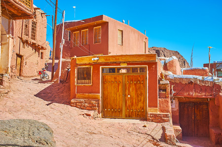 The narrow curved street leads to the mountain top, running among the restored old red-ochre houses of local villagers, Abyaneh, Iran.の写真素材