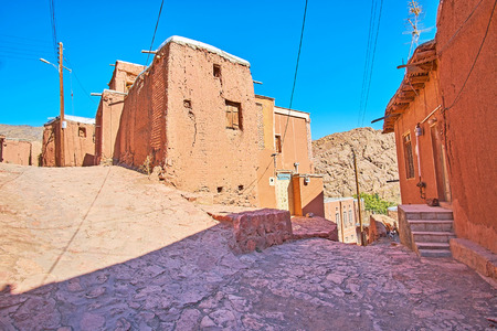 The medieval stone street branches into different directions with a view on the old adobe edifices in the middle, Abyaneh, Iran.の写真素材