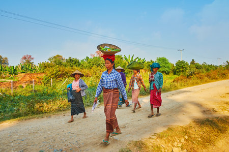 AVA, MYANMAR - FEBRUARY 21, 2018: The group of Burmese peasant women goes back after field work with food bags on their heads, on February 21 in Ava.のeditorial素材