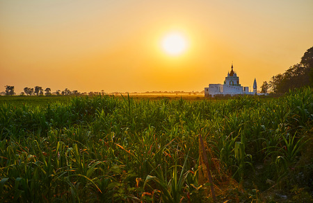The bright sunset above the farmlands of Amarapura, the hazy Shwe Modeptaw Pagoda  dominates the plain, Myanmar.の写真素材