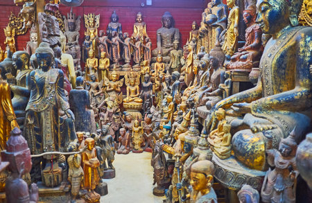MANDALAY, MYANMAR - FEBRUARY 21, 2018: Interior of store in Shwe-gui-do Quarter with large amount of handmade wooden sculptures, mostly on Buddhist theme or mythic motives, on February 21 in Mandalay.のeditorial素材