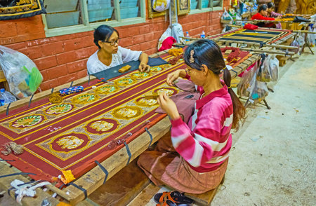 MANDALAY, MYANMAR - FEBRUARY 21, 2018: Artisans embroider large tapestry with traditional Burmese patterns with elephants and peacocks in workshop of Shwe-gui-do Quarter, on February 21 in Mandalay.のeditorial素材