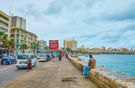 ALEXANDRIA, EGYPT - DECEMBER 19, 2017: The heavy grey clouds on a windy morning above the Corniche Avenue, full of cars and pedestrians, on December 19 in Alexandria.のeditorial素材