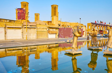 YAZD, IRAN - OCTOBER 18, 2017: The medieval mudbrick badgirs (windcatchers) of the yakhchal (ice chamber) are reflected in fountain of Amir Chakhmaq square, on October 18 in Yazdのeditorial素材
