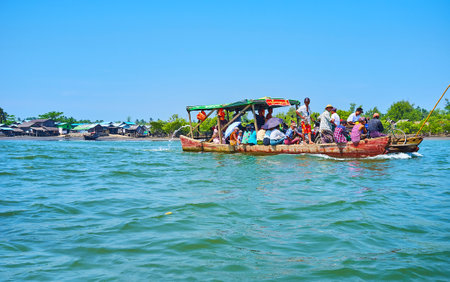 CHAUNG THA, MYANMAR - MARCH 1, 2018: The crowded old wooden ferry floats across the Kangy river from...