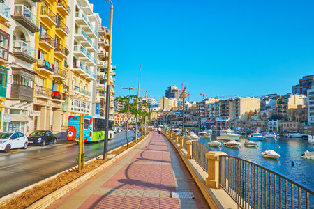 ST JULIANS, MALTA - JUNE 20, 2018: The walk along Spinola Bay harbor with a view on bobbing boats and tourist cafes on shore, on June 20 in St Julians.のeditorial素材