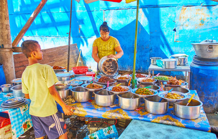 YANGON, MYANMAR - FEBRUARY 17, 2018: Chinatown street food cafe at the shabby house wall with wide range of local dishes in metal pans, on February 17 in Yangon.のeditorial素材