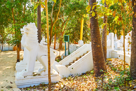 Enjoy the shady garden of Shwethalyaung Buddha Temple and watch the scenic medieval chinthe leogrpyphs statues, guarding the pagoda, Bago, Myanmarの写真素材