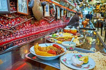 ISFAHAN, IRAN - OCTOBER 21, 2017: Enjoy traditional dinner in Azadegan Tea House, offering best dishes of Iranian cuisine, such as beryani, stewed vegetables, Persian tea, on October 21 in Isfahan.のeditorial素材