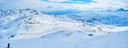 Panoramic winter Alpine skyline of Dachstein massif from the snowy slopes of Krippenstein mount with numerous ski trails and showshoers' routes, Salzkammergut, Austria.の写真素材