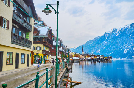 HALLSTATT, AUSTRIA - FEBRUARY 21, 2019: Seestrasse is the lakeside promenade and center of tourist activity in town, people walk here, enjoy  Hallstatter see (lake) and visit local stores, on February 21 in Hallstatt.のeditorial素材