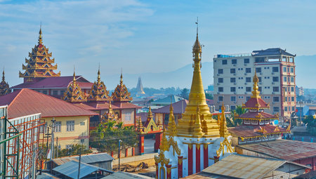 The golden stupa of Tain Nan Pagoda and pyatthat roof of the monastery, rising over the roofs of the tourist village of Nyaungshwe, Myanmar.のeditorial素材