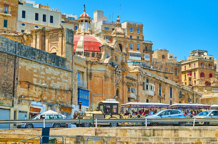 VALLETTA, MALTA - JUNE 19, 2018: The tourist train, driving along Quarry Wharf with a view on city...