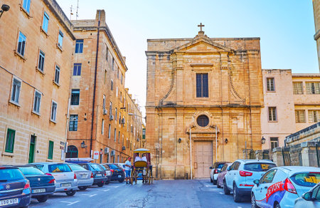 VALLETTA, MALTA - JUNE 19, 2018: The St Mary Magdalene church faces North street, occupied with parked cars, on June 19 in Valletta.のeditorial素材