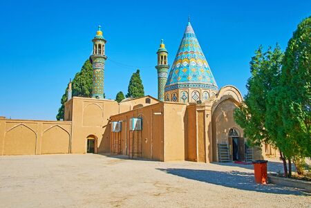 Exterior of adobe bulding of Imamzadeh Ibrahim Mausoleum with two slender minarets and conical roof, decorated with turquoise tilework, Kashan, Iranの写真素材
