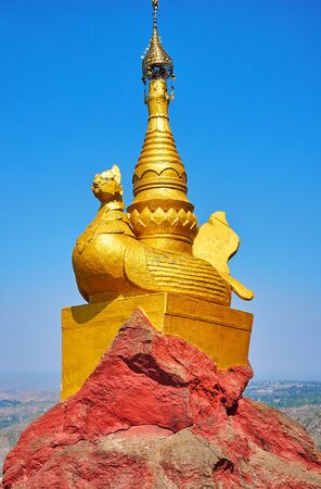 The small votive stupa atop the statue of golden Karaweik duck, standing on the edge of the rock in Popa Taung Kalat Monastery, Myanmarの写真素材