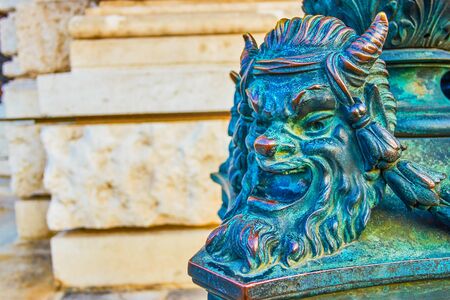 The bronze head of the faun is a decorative element of the base of the streetlights of Burgtheater in Vienna, Austriaの写真素材