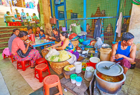 POPA, MYANMAR - FEBRUARY 26, 2018: The food sellers offer tasty dishes of Burmese cuisine in market of Taung Kalat Temple, pilgrims have lunch at small tables in hall of market, on February 26 in Popaのeditorial素材
