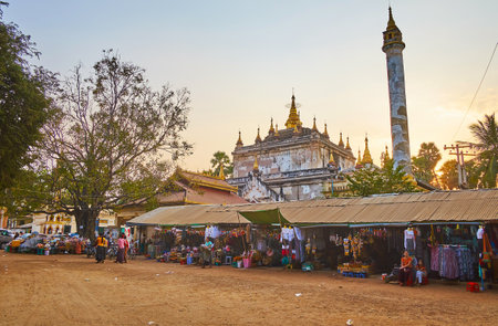 BAGAN, MYANMAR - FEBRUARY 24, 2018: The stalls of garment market, located at the entrance to the medieval Manuha Temple with tall Buddhist Pillar and many small golden stupas on the roof, on February 24 in Bagan.のeditorial素材