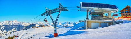 ZELL AM SEE, AUSTRIA - FEBRUARY 28, 2019: Panorama of Kettingbahn ski lift with its top station, tower and riding chairs with sportsmen, going to the top of Schmitten mount, on February 28 in Zell Am See.のeditorial素材
