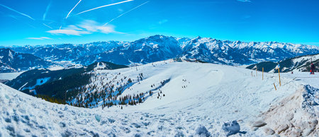 Fine sunny weather on Schmittenhohe mount is perfect chance to observe the winter panorama and enjoy the snowy slopes, sharp Alpine peaks and bright blue sky with numerous contrails, Zell am See, Austriaのeditorial素材