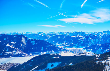 The light blue haze covers the sharp Alpine peaks and snowy slopes, seen from the peak of Schmittenhohe mount, Zell am See, Austriaのeditorial素材