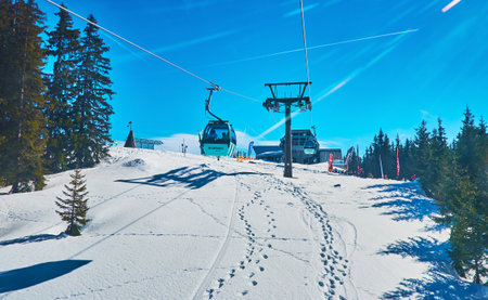 ZELL AM SEE, AUSTRIA - FEBRUARY 28, 2019: Enjoy the cableway journey over the snowy slopes of Schmitten mount in gondola of Areitbahn air lift, on February 28 in Zell Am Seeのeditorial素材