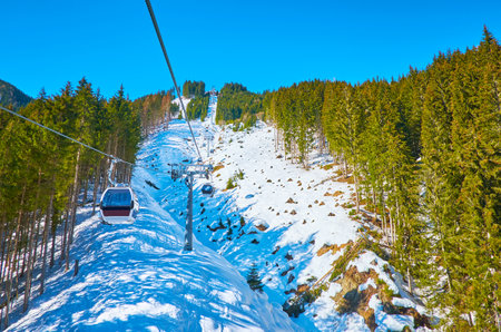 The snowy slope of Schmitten mount with lush pine forests and riding gondolas of Trassxpress cableway, Zell am See, Austriaのeditorial素材