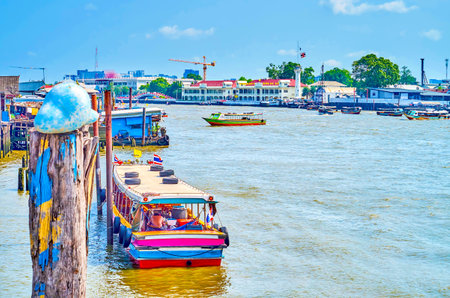 The old wooden passenger boat moored at the piles of the Chao Phraya river bank in Bangkok, Thailandのeditorial素材
