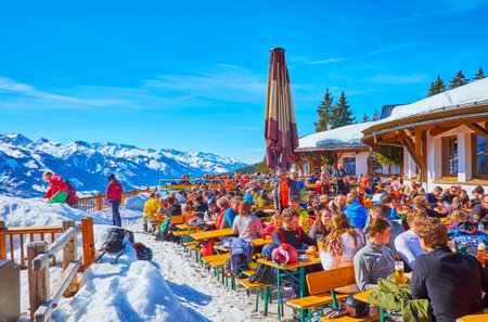 ZELL AM SEE, AUSTRIA - FEBRUARY 28, 2019: Crowded open air terrace of the lounge cafe, located on snowy Areitalm Alpine meadow, sportsmen take a rest after the downhill, on February 28 in Zell Am See.のeditorial素材