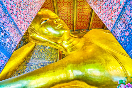 BANGKOK, THAILAND - APRIL 22, 2019: The large golden sculpture of Reclining Buddha lies on the tiled pillow in beautifully decorated Viharn Phranorn temple in Wat Pho complex, on April 22 in Bangkokのeditorial素材