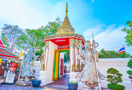 BANGKOK, THAILAND - APRIL 22, 2019: The beautifully decorated entrance gates to Wat Pho temple with sculptures of guardians and colorful tiled shaped crown with the spire, on April 22 in Bangkokのeditorial素材