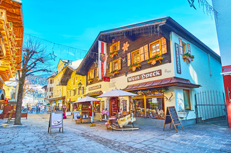 ZELL AM SEE, AUSTRIA - FEBRUARY 28, 2019: The souvenir shop in traditional Alpine house, decorated with flags, plants in pots, Christmas garlands and vintage wooden sleigh at the entrance, on February 28 in Zell Am Seeのeditorial素材