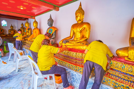 BANGKOK, THAILAND - APRIL 22, 2019: The renovators work in gallery of Phra Rabiang cloister in Wat Pho temple, cleaning and painting sculptures and pedestal of Lord Buddha, on April 22 in Bangkokのeditorial素材