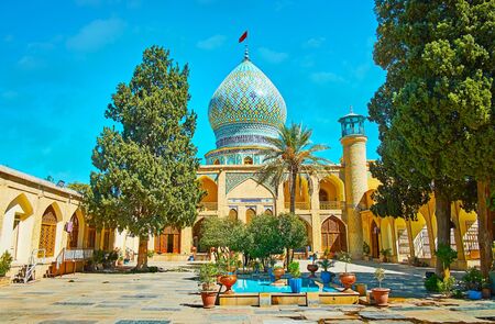 Exterior of medieval Ali Ibn Hamzeh Holy Shrine, decorated with arched niches, carved wooden Persian screens, scenic bulbous dome with rich tile patterns and small garden, Shiraz, Iranの写真素材