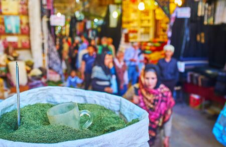 SHIRAZ, IRAN - OCTOBER 14, 2017: The crowded alleyway of historical Vakil Bazaar with a view on the bag of dried pennyroyal herb on the foreground, on October 14 in Shiraz.の写真素材