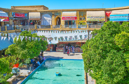 SHIRAZ, IRAN - OCTOBER 14, 2017: The scenic area of Saraye Moshir Bazaar with fountain in the middle, shady trees with banches and multiple stores around small garden, on October 14 in Shiraz.のeditorial素材
